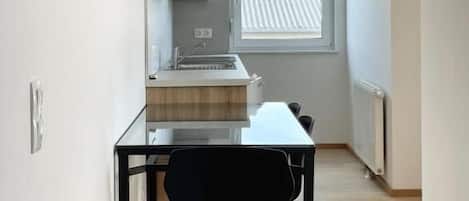 A compact kitchen with a dining table and chairs, a window with a view, and a radiator.