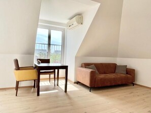 Una habitación con una mesa de comedor y sillas, un sofá y un ventanal con vistas.