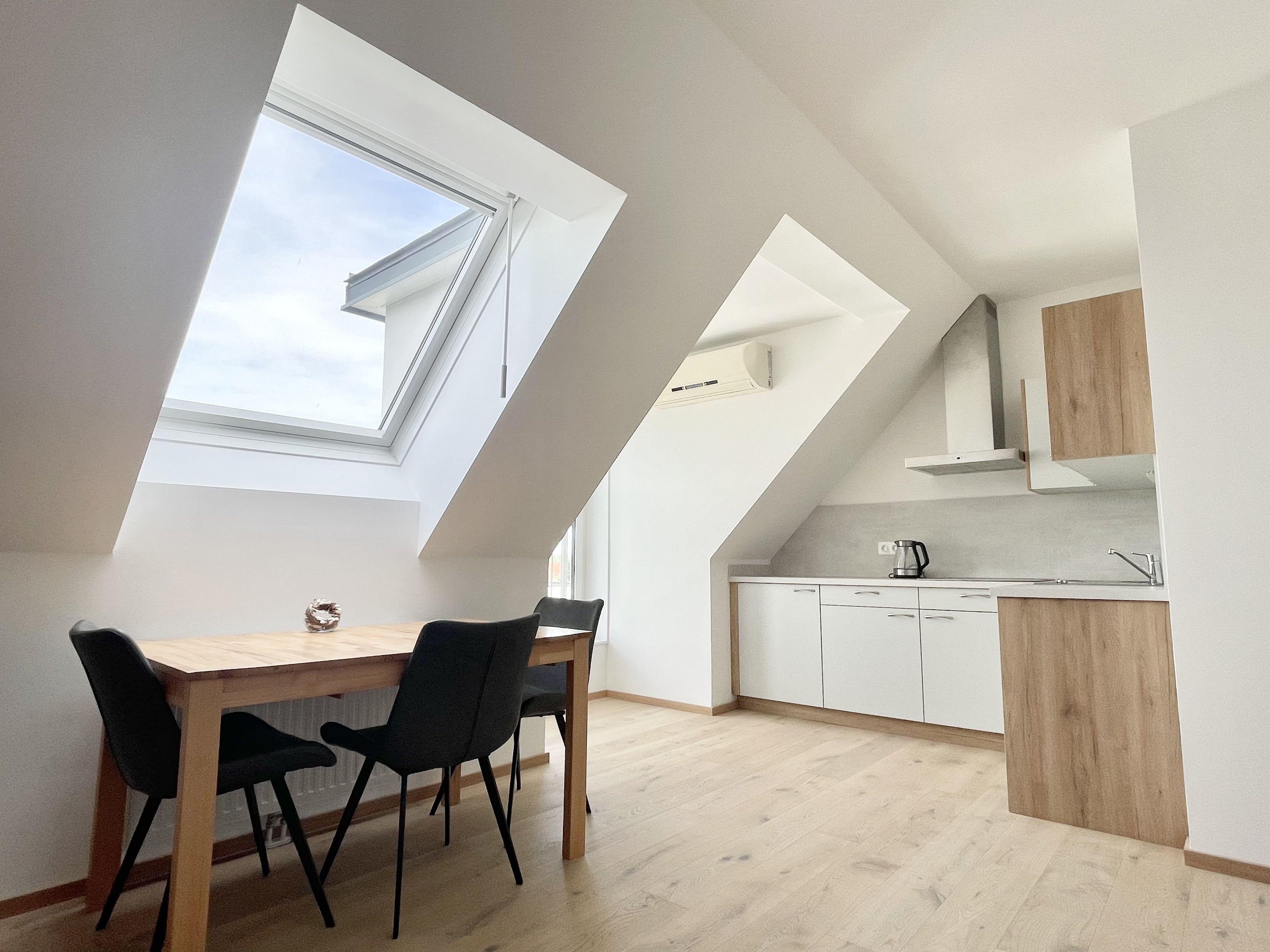 A modern kitchen with white cabinets, a wooden countertop, and a skylight.
