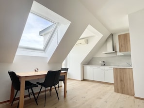 Una cocina moderna con armarios blancos, encimera de madera y tragaluz.