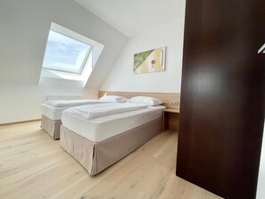 Ein Schlafzimmer mit Dachfenster, einem Bett, einem Nachttisch und einem Wandbild.