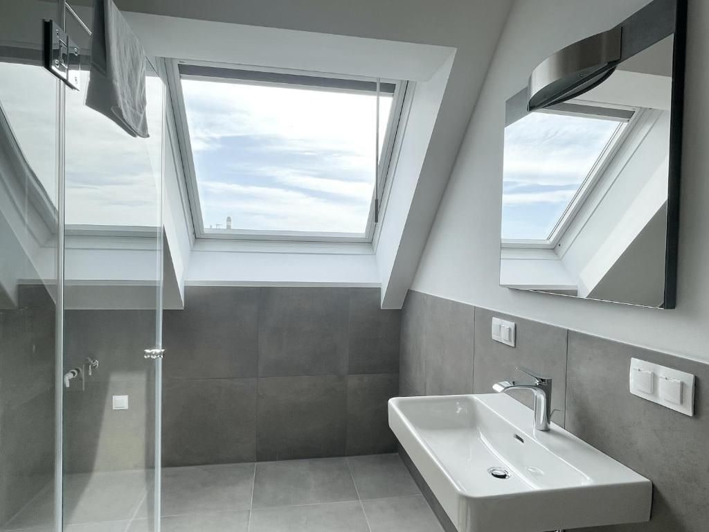 A modern bathroom with a skylight, a large mirror, and a walk-in shower.