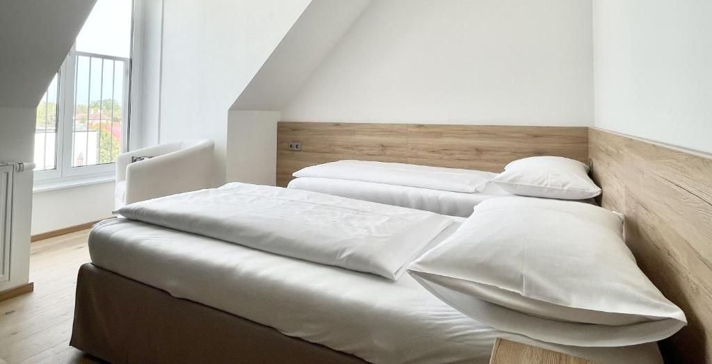 Ein Schlafzimmer mit schrägen Wänden, einem Holzkopfteil und einem großen Fenster.