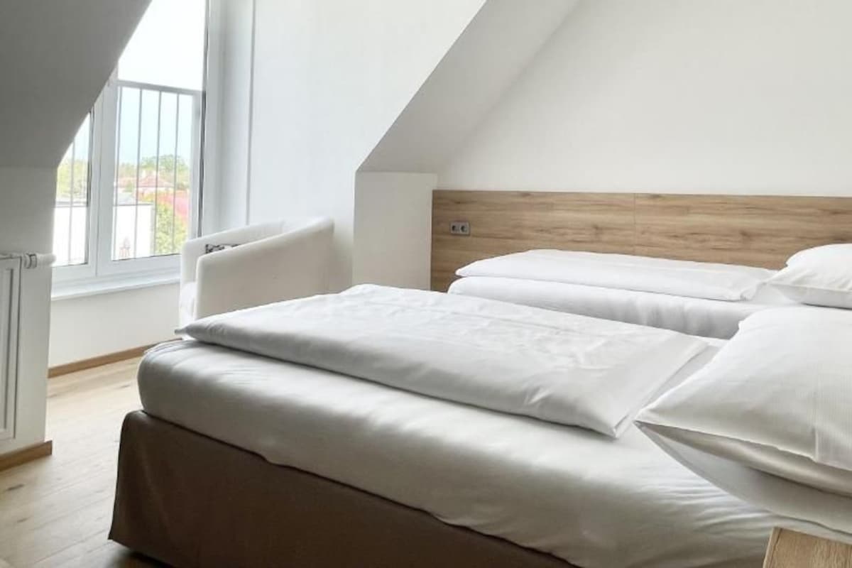 Un dormitorio con techo inclinado, cabecera de madera y un gran ventanal.