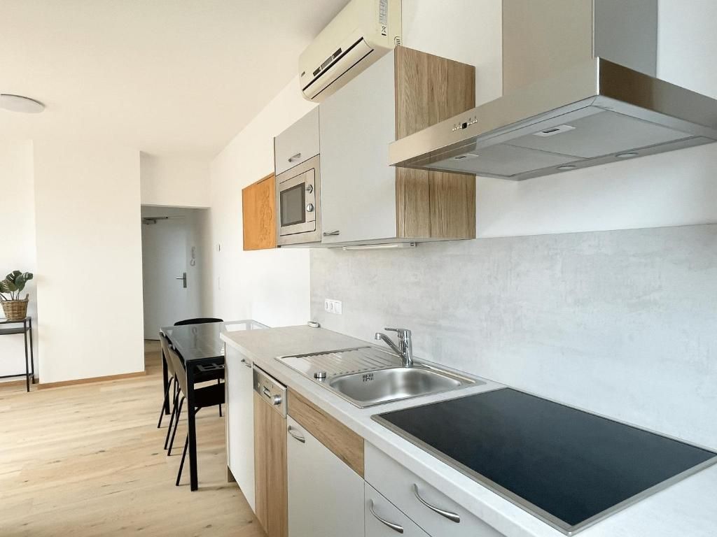 A modern kitchen with a built-in stove, a sink, and wooden cabinets.