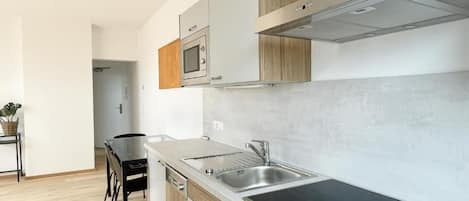 A modern kitchen with a built-in stove, a sink, and wooden cabinets.