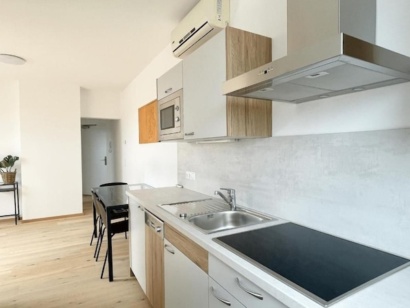 Cocina moderna con estufa integrada, pileta y alacenas de madera.