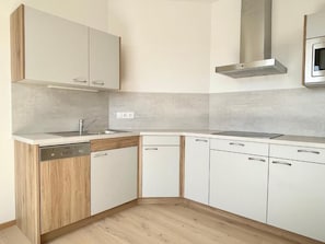 Una cocina moderna con armarios blancos, lavavajillas y una campana extractora de acero inoxidable.