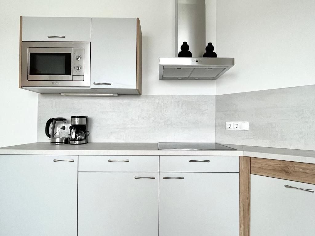 A modern kitchen with a built-in microwave, a coffee maker, and a stainless steel range hood.