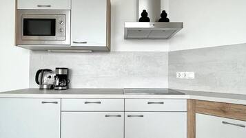 A modern kitchen with a built-in microwave, a coffee maker, and a stainless steel range hood.