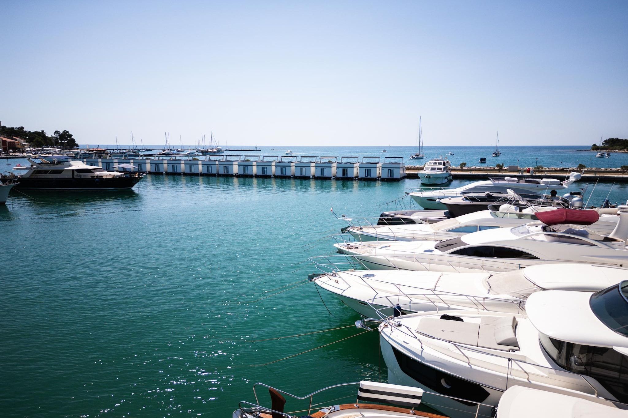 Un port de plaisance où sont amarrés différents types de bateaux, avec une eau calme et un ciel dégagé.