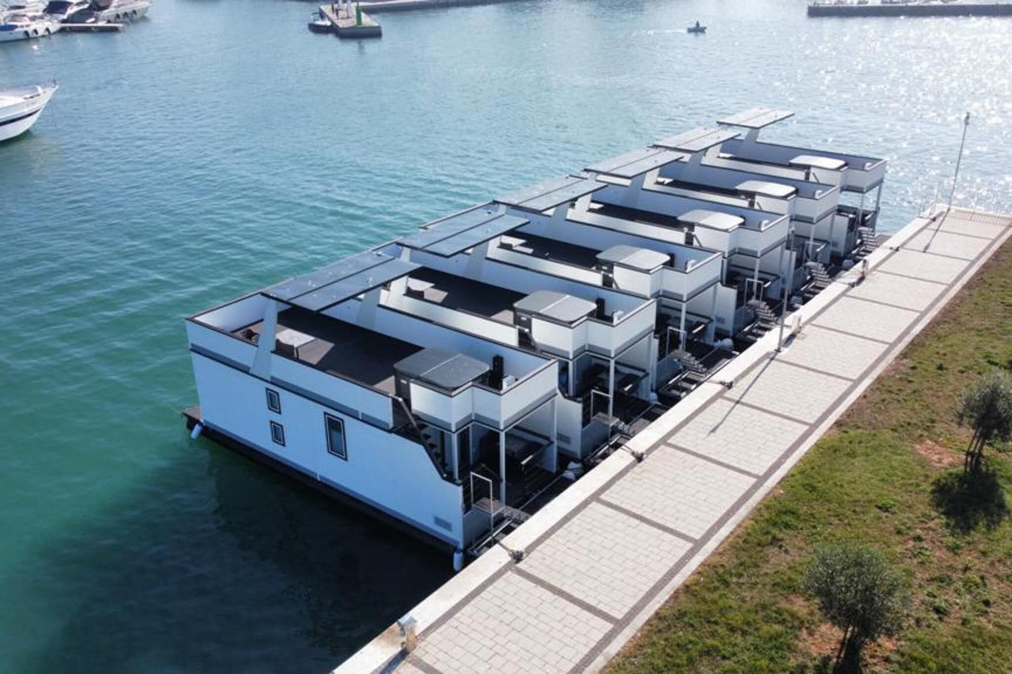 Una propiedad frente al mar con varios edificios conectados, probablemente viviendas o locales comerciales, y un muelle que se adentra en el agua.