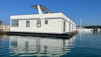 Una casa flotante moderna con techo plano, ventanas grandes y una pequeña terraza.