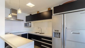 Eine moderne Küche mit einem Edelstahl-Kühlschrank, einer Spüle mit zwei Becken und einer Mikrowelle.