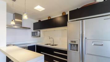 A modern kitchen with a stainless steel refrigerator, a built-in microwave, and a double sink.