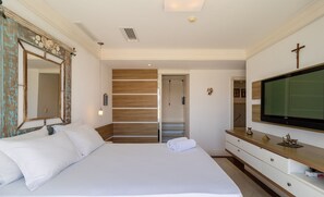 Ein Hotelzimmer mit einem großen Bett, einem Holzschrank, einem Fernseher und einem Kreuz an der Wand.