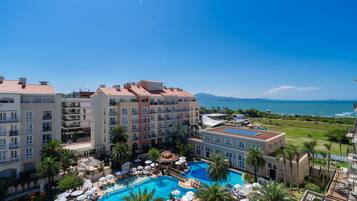 A hotel with a swimming pool, multiple balconies, and a view of the ocean.