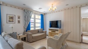 A living room with a sofa, armchair, TV, and a wicker chair. - Exclusive Penthouse Luxury Resort Jurere Ilc2508 (Florianópolis)