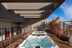 Une terrasse sur le toit avec deux bains à remous et une vue sur les toits de la ville.