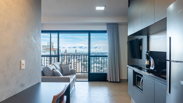 A modern apartment with a balcony, a sofa, a dining table, and a kitchen area. - Studio in Condo With Gym Idvb2703 (Goiânia)