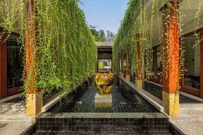 Un pasillo con plantas colgantes y una fuente central.