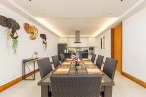 Ein moderner Essraum mit einem Glastisch, schwarzen gewobenen Stühlen und dekorativen Elefantenköpfen an der Wand.
