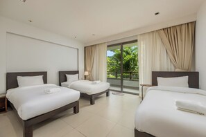 Habitación de hotel con dos camas, un ventanal con cortinas y vistas a zonas verdes.
