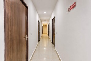 A hotel corridor with wooden doors, a 'No Smoking' sign, and a tiled floor. - Super Collection O Sector 5 Ghaziabad (Ghaziabad)