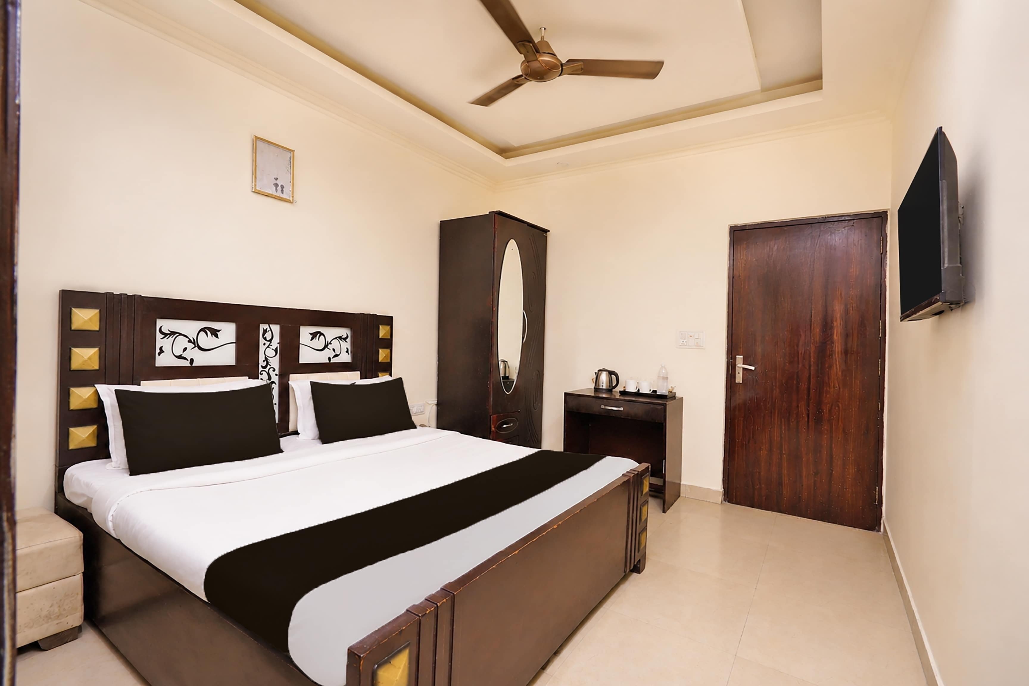 A hotel room with a bed, bedside table, wardrobe, and a ceiling fan.