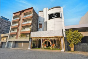 Un edificio de varios pisos con una entrada a nivel de calle adornada con arreglos florales.