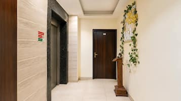 Un pasillo con pared de mármol, puerta de madera y un letrero en la pared.