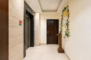 A hallway with a marble wall, a wooden door, and a wall-mounted sign. - Super Collection O Sector 5 Ghaziabad (Ghaziabad)