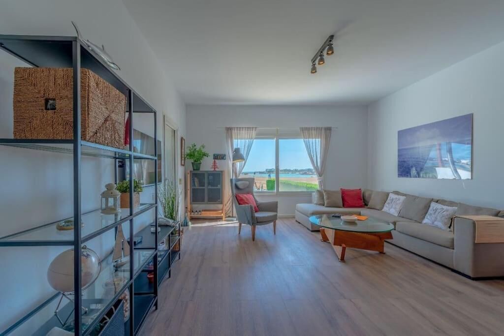 Ein modernes Wohnzimmer mit Sofa, Couchtisch und Regalen. Ein Fenster mit Vorhängen bietet Blick ins Freie.
