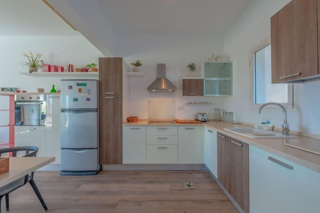 A modern kitchen with white cabinets, a built-in oven, and a stainless steel refrigerator.