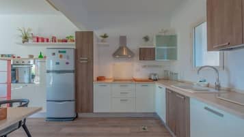 A modern kitchen with white cabinets, a built-in oven, and a stainless steel refrigerator.
