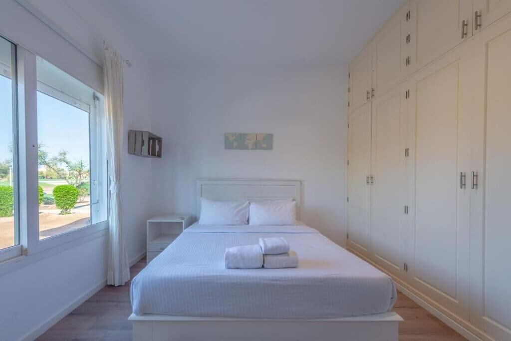 Un dormitorio con una cama grande, una mesita de noche, un armario y una ventana con cortinas.