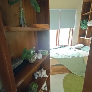 Ein Zimmer mit einem Bett, einem Holzschrank und einem Fenster mit Jalousien.