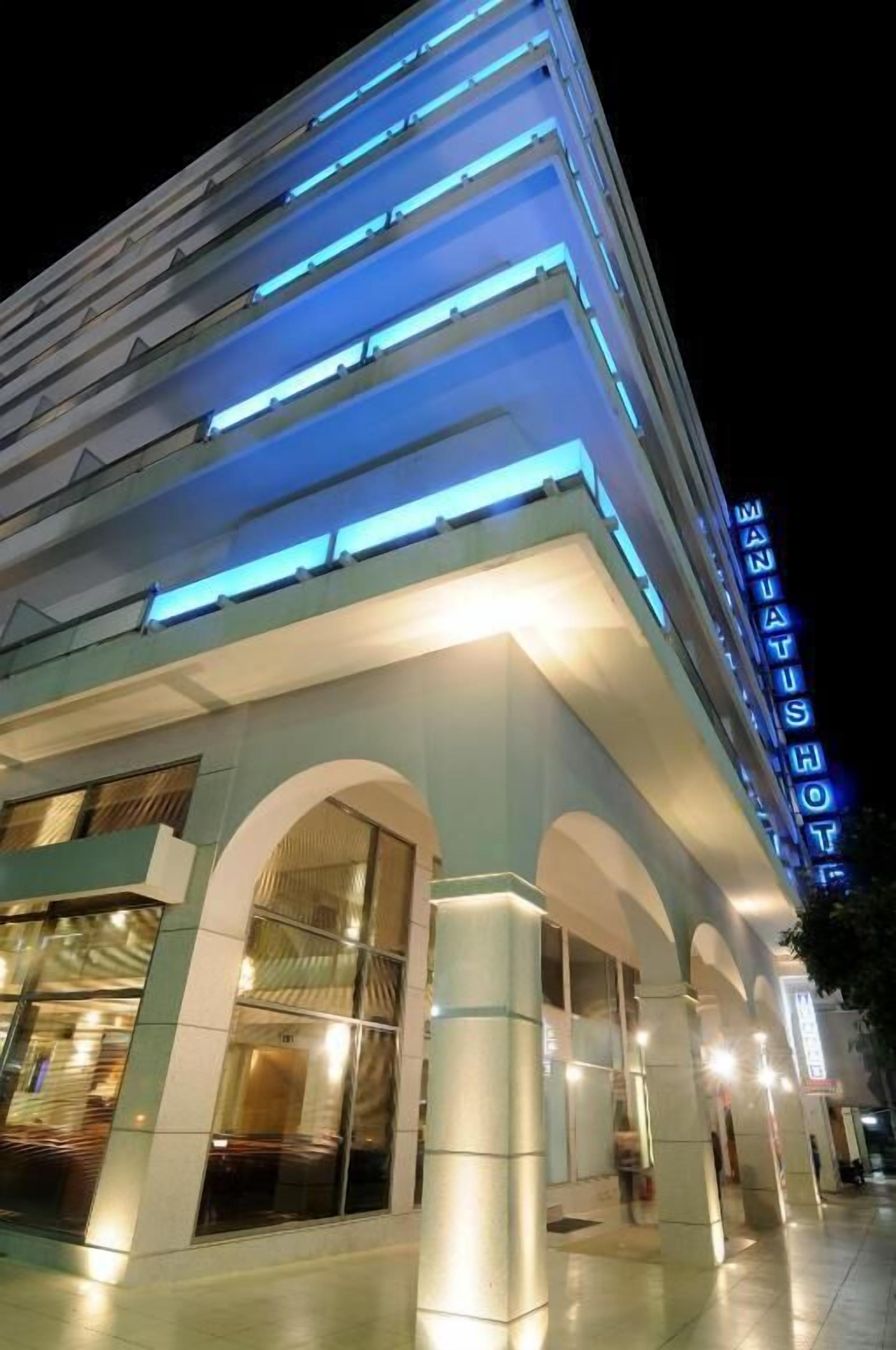 A modern hotel with a prominent 'HOTEL' sign, multiple floors, and a well-lit facade.