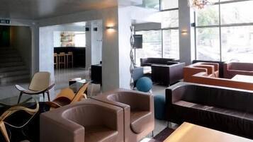 A modern interior with a large chandelier, seating area, and large windows.