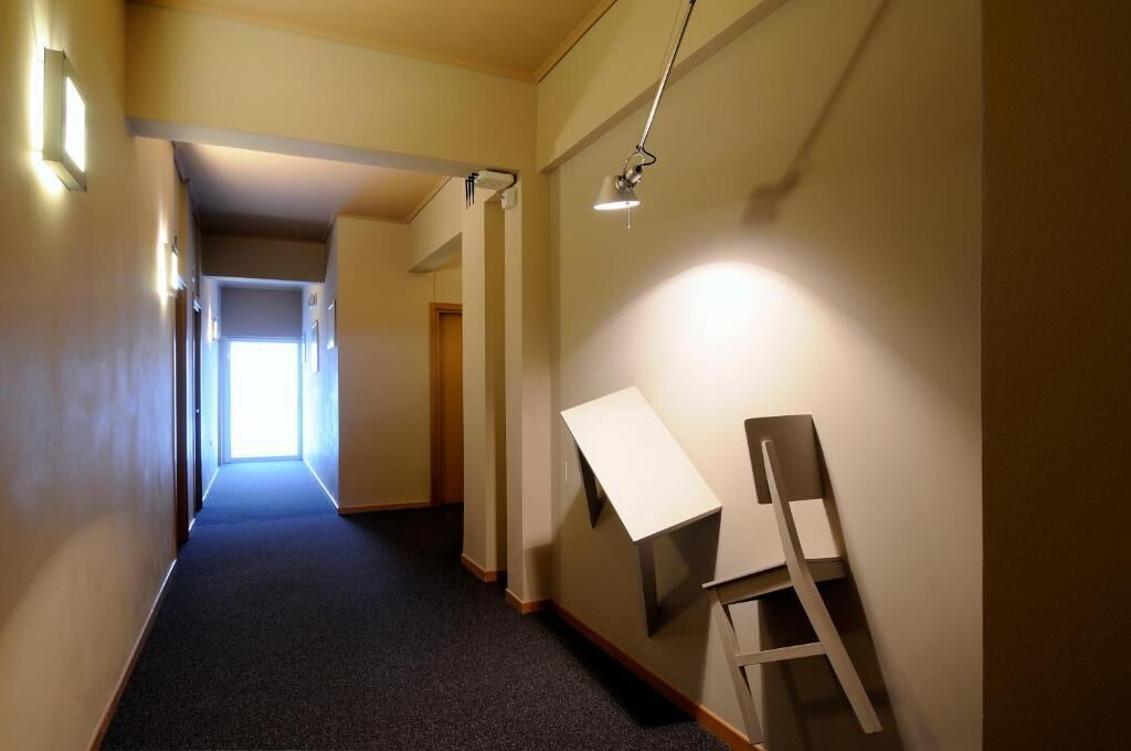A hallway with a carpeted floor, a desk, and a chair.