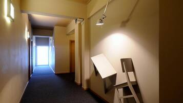 A hallway with a carpeted floor, a desk, and a chair.