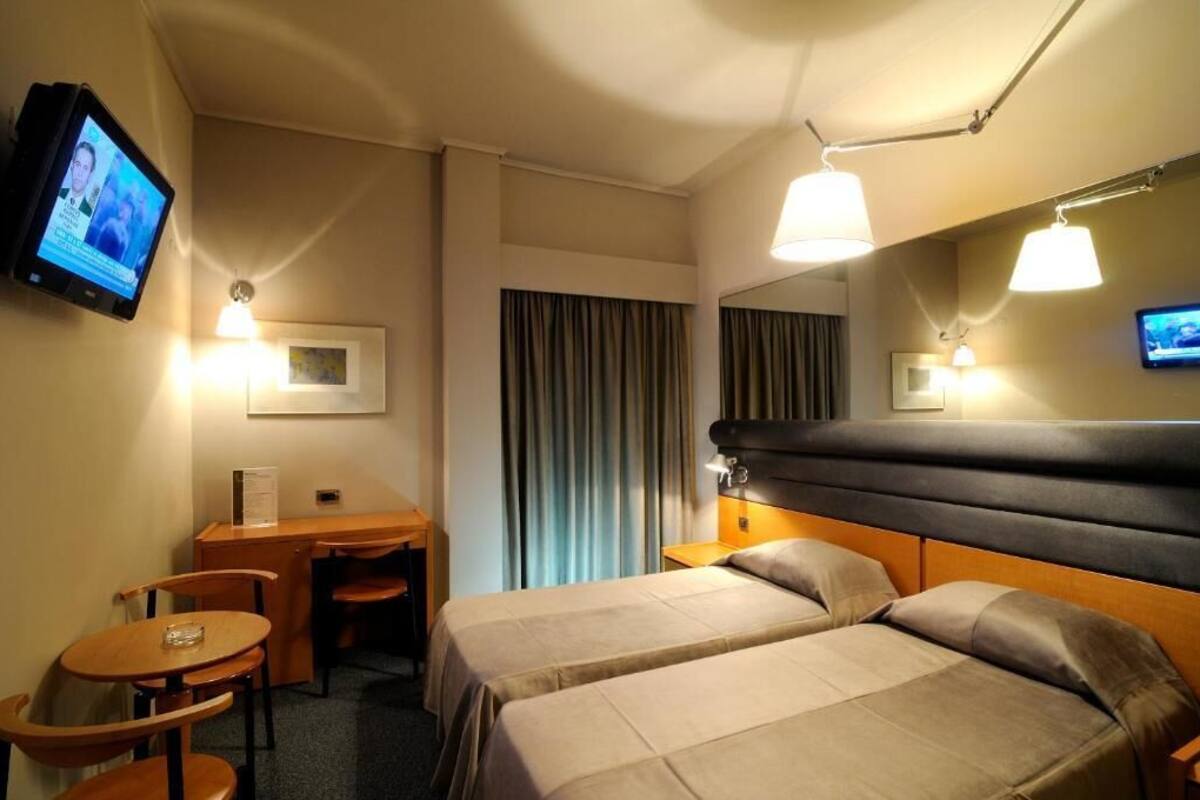 Habitación con 2 camas individuales, vista a la ciudad | Espacio para trabajar con laptop y tabla de planchar con plancha
