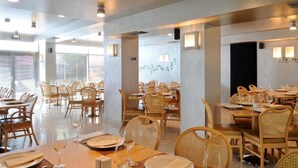 Un restaurante con varias mesas y sillas, decorado con velas y copas de vino.