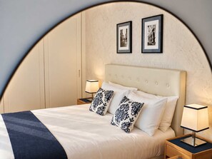 A hotel room with a bed, two bedside tables, a nightstand, and two framed pictures on the wall. - Mare Blu - Portopiccolo Apartments (Sistiana)