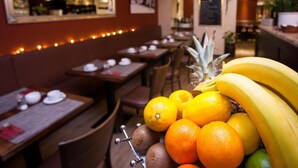 A restaurant interior with tables, chairs, and a fruit display.