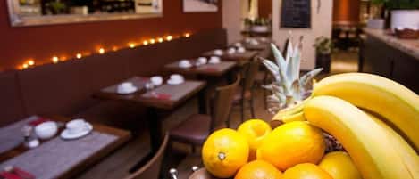 A restaurant interior with tables, chairs, and a fruit display.