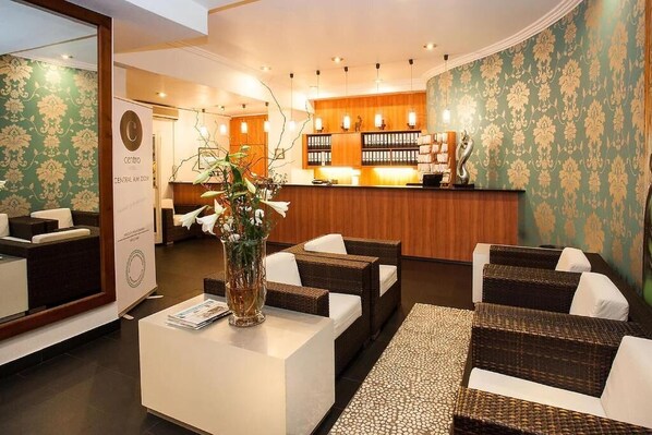 Un hall d’hôtel comprenant un comptoir d’accueil, un espace salon et un grand miroir.