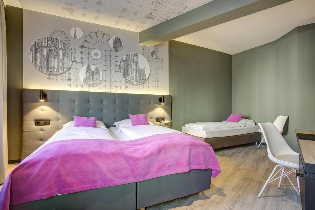 A hotel room with two beds, a seating area, and a wall with circular artwork.
