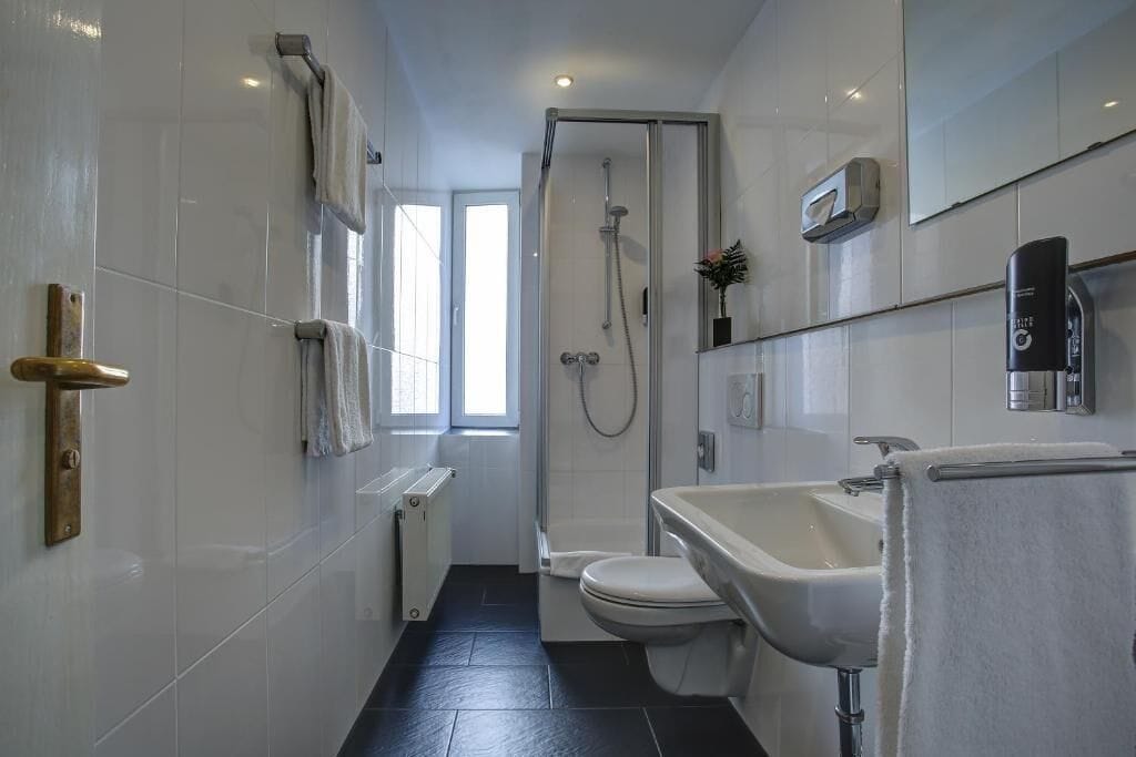 A modern bathroom with a shower, toilet, and sink.