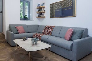 A grey sofa with two pink cushions, a patterned throw, and a small table with decorative items. - Exclusive Syntagma & Plaka 2BD Townhouse (Athina)